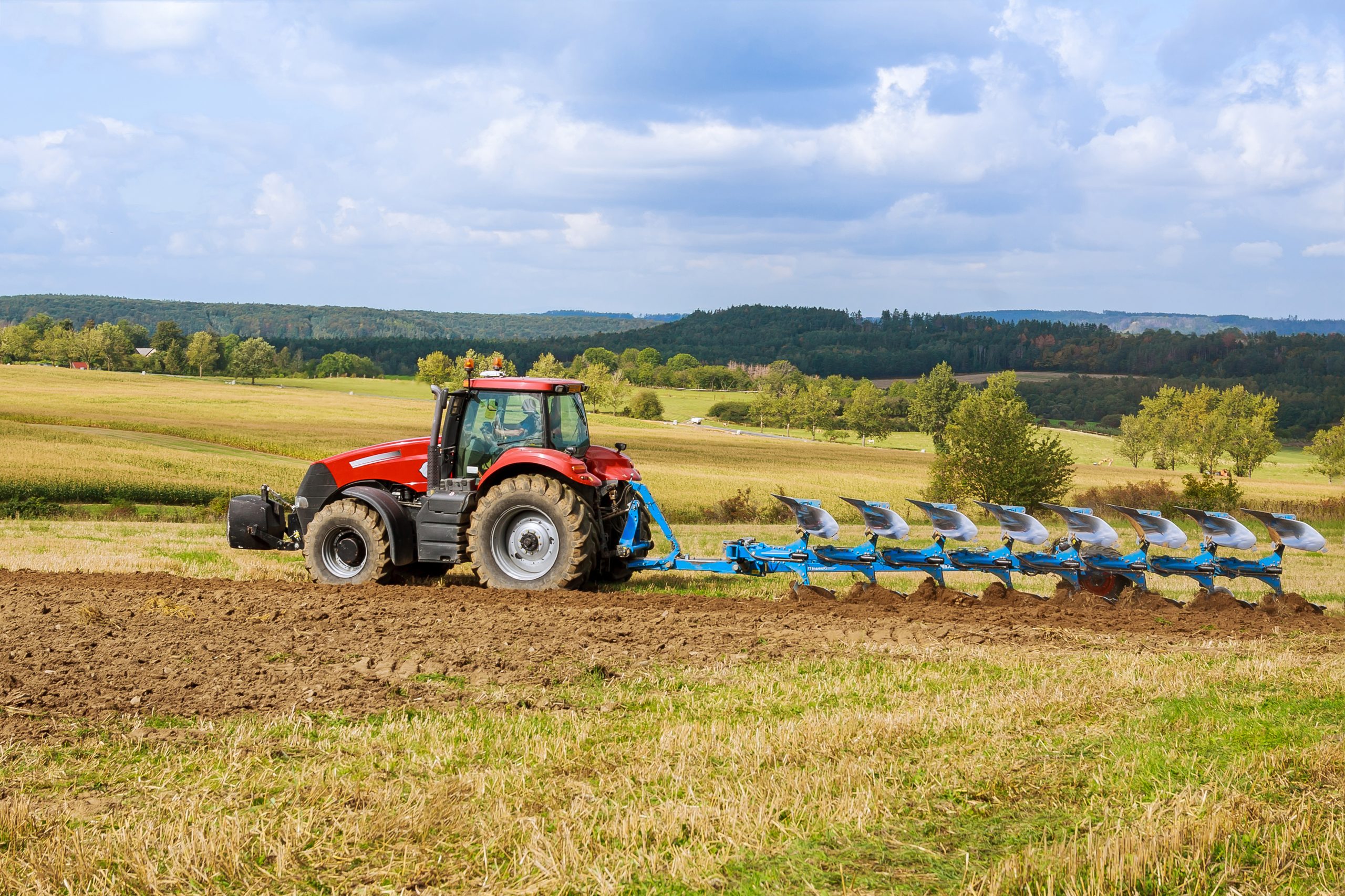 A tractor with a large plow plows a field. Tractor with agricultural attachment. Preparation of land for sowing.